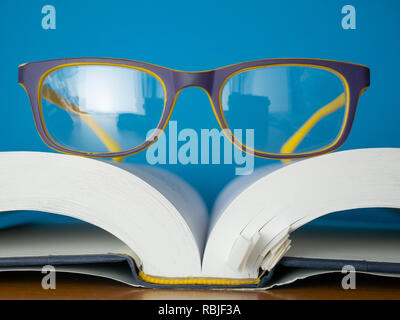 macro photo of reading glasses lay on top of opened book. education and learing concept Stock Photo