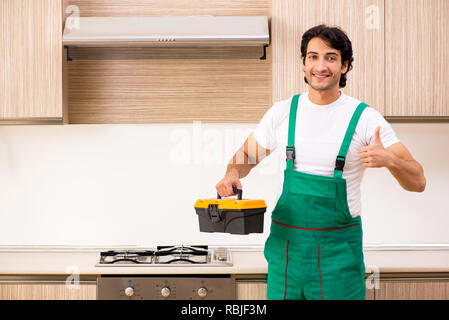 Young contractor repairing oven in kitchen Stock Photo