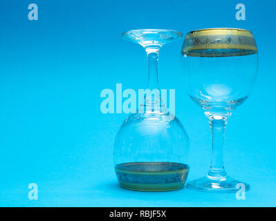 two empty wine glasses on blue background. one glass is upside down, bottom up Stock Photo
