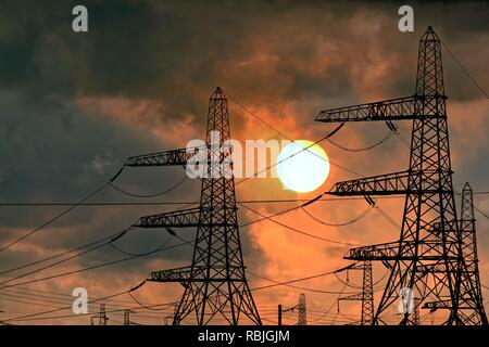 National Grid electricity pylons at Dungeness Kent against a dramatic sunset, England UK Stock Photo