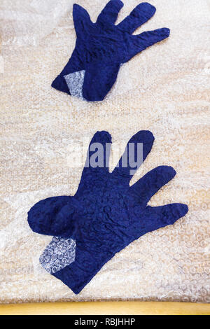 workshop of hand making a fleece gloves from blue Merino sheep wool using wet felting process - felted gloves after rolling and pressing Stock Photo