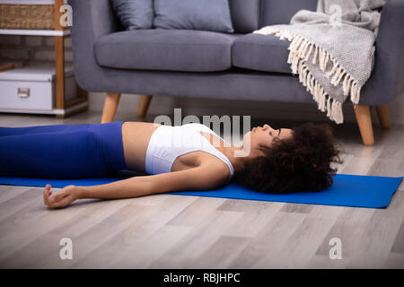 Athletic Young Woman Lying On Blue Yoga Mat Over The Hardwood Floor Stock Photo