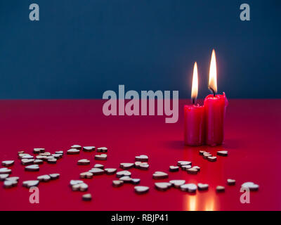 Concept of love Still life with red lit candles and small wood hearts Stock Photo
