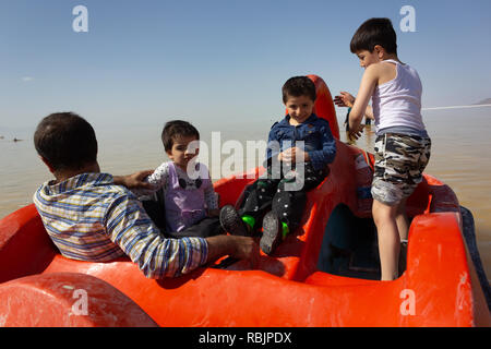 A man is riding a pedal boat with his children on the Urmia Lake, West Azerbaijan province, Iran Stock Photo