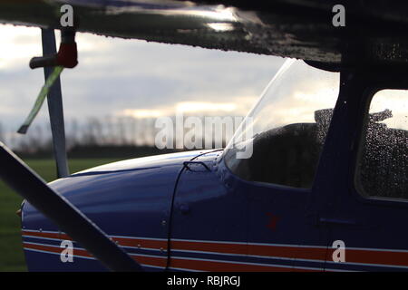 A Cessna 172 sits on the airfield in a dusky glow, fresh from the rain... Stock Photo