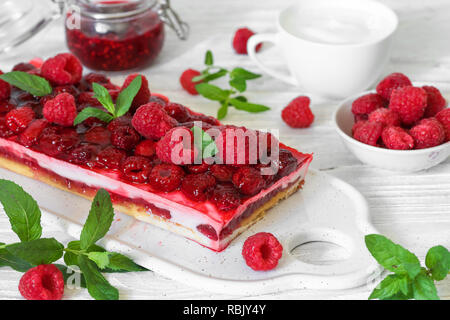 raspberry creamy cake or cheesecake with freash berries, mint, jam and cup of cappuccino for breakfast on white background Stock Photo