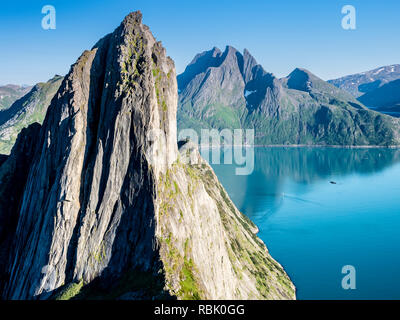 Mountain Segla seen from mountain Hesten,  small sailing boat on the calm sea, peak Breidtinden in the back, island Senja, Troms, Norway Stock Photo