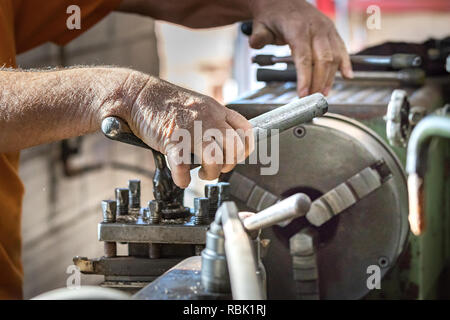 A male worker operating a lathe inside an aluminium factory. Stock Photo