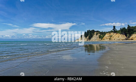 The tide coming in at Kina Beach with the cliffs reflecting in the wet sand, Tasman, near Motueka, New Zealand Stock Photo