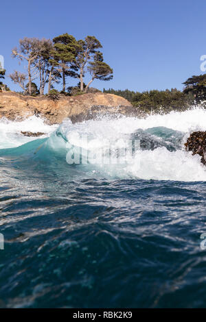 A wave breaks over a wash rock in Russian Gulch State Park. Stock Photo