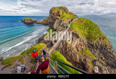 Tourists and visitors explore and walk across the Rope Bridge at Carrick-A-Rede and Larrybane Bay on the West Coast of Ireland. Stock Photo