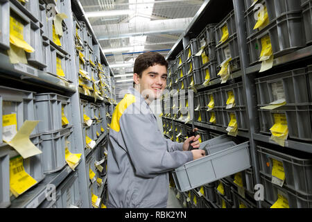 Worker in warehouse among long shelves with a variety of boxes Stock Photo