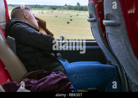 Young woman sleeping on a bus while traveling to a destination in Ireland. Stock Photo