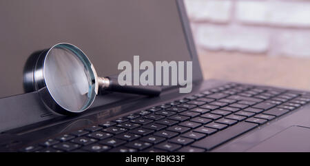 magnifying glass on black laptop Stock Photo