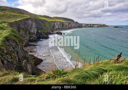 Tourists and visitors explore and walk across the Rope Bridge at Carrick-A-Rede and Larrybane Bay on the West Coast of Ireland. Stock Photo