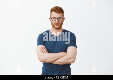 Strict european redhead male teacher being angry at student failing exam. Portrait of serious-looking handsome mature male with bristle in cool glasses, staring at camera, crossing fingers on chest Stock Photo