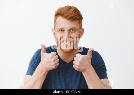 Supportive and attractive adult redhead male with bristle liking great plan raising hands, showing thumbs up, smiling joyfully, accepting nice idea or cheering friend who trying talk to charming woman Stock Photo