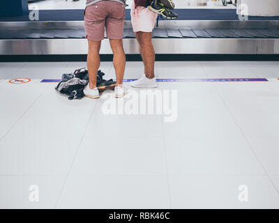 BANGKOK, THAILAND-November 5, 2018: Two tourists wearing shorts and sneakers waiting luggages at the baggage claim in Don Muang International airport 
