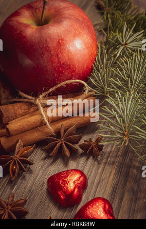 Christmas layout concept on wooden background with bunch of cinnamon anise stars, pine foliage, clementine heart shaped red candies and common walnuts Stock Photo