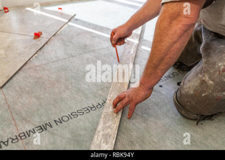 Man Using Marking Pencil To Draw Tile Grid On Floor Stock Photo