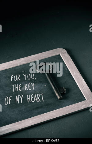 a key on a chalkboard where you can read the text for you the key of my heart in a chalkboard, on a dark background with some blank space on top Stock Photo