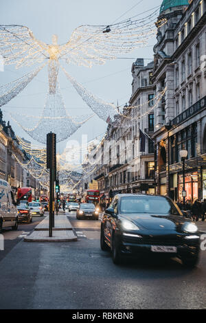 London, UK - January 5,2019: Buses, cars and pedestrians under angel Christmas lights on Regent Street in the evening, motion blur.  Regent Street is  Stock Photo
