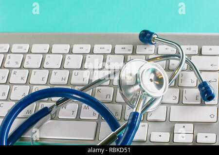 closeup of the desk of a doctors office with a stethoscope in the foreground and a bottle with pills in the background, selective focus. Stock Photo