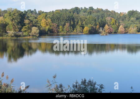 Tarrytown reservoir lake on a clear day in early autumn with some fall tree colors and reflections in the water Stock Photo