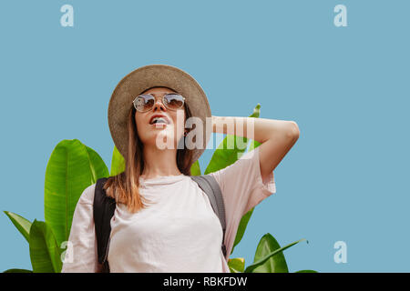 Amazed woman near tropical plant looking away Stock Photo