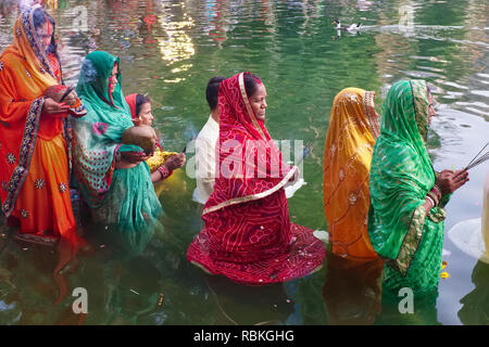 Women standing in Banganga Tank, Mumbai, India, in prayer looking towards the setting sun, celebrating Hindu festival Chhath Puja Stock Photo