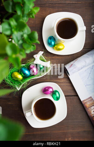 Two cups of coffee with chocolate eggs in Easter morning over wooden table Stock Photo