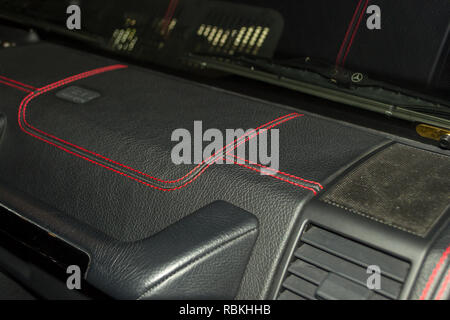 A view of a part of the interior of the car panel from leather of black color, stitched double thread of red color with contrast stitching in a vehicl Stock Photo