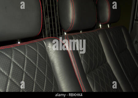 A view of a part of the interior of the car seat from leather of black color, stitched double thread of red color with contrast stitching in a vehicle Stock Photo