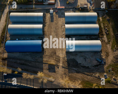 Aerial view of the six round cylindrical storage hangars on a bright autumn day. Industrial buildings for manufacturing in the city near the houses. Stock Photo