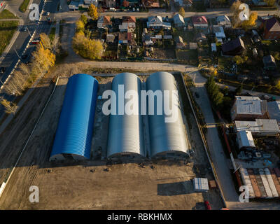 Aerial view of the six round cylindrical storage hangars on a bright autumn day. Industrial buildings for manufacturing in the city near the houses. Stock Photo