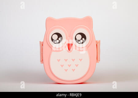 Lunchbox in the form of a pink owl for preserving and carrying homemade food or sandwiches during working day on white isolated background. Stock Photo