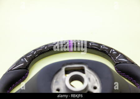 Close-up of the upper part of an exotic designer steering wheel made of black carbon fiber with perforated leather stitched with purple thread on the  Stock Photo