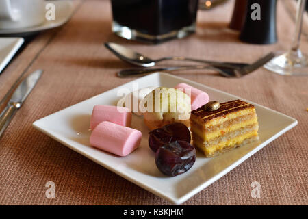 Set of sweets on white plate on table in cafe Stock Photo