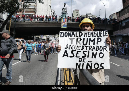 Caracas, Miranda, Venezuela. 10th Jan, 2019. A man holding a placard with the message 'Donald Trump: Kidnapper and murderer of childrens''.Venezuelan President Nicolas Maduro started a second term, defying critics in the United States and Latin America who called him an illegitimate usurper of a nation where economic chaos has wrought a humanitarian crisis. The National Assembly calls the Maduro government a ''dictatorship and usurpation of power.'' Currently Venezuela is experiencing its worst economic crisis with an inflation rate of over 1,000,000% (Credit Image: © Roman Camacho/SOP Stock Photo