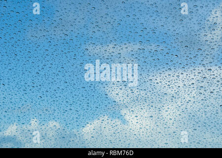 Raindrops on the windshield; in the background blue sky and white clouds, California Stock Photo