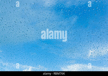 Raindrops on the windshield; in the background blue sky and white clouds, California Stock Photo