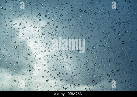 Raindrops on the windshield; in the background dark sky and a break in the clouds, California Stock Photo