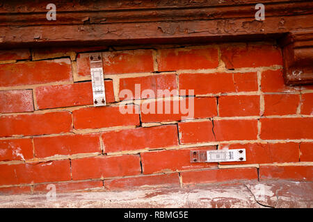 A pair of crack gauges monitor the size of cracks in a brick wall Stock Photo