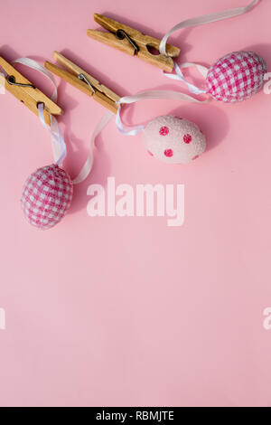 colorful Easter Eggs with Cross hanging on line from clothespins.Still Life Easter eggs hanging on a rope on pink background. Easter holiday concept.Copy space Stock Photo