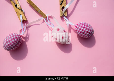 colorful Easter Eggs with Cross hanging on line from clothespins.Still Life Easter eggs hanging on a rope on pink background. Easter holiday concept.Copy space Stock Photo