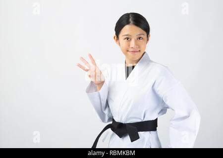 Young beautiful woman wearing karate suit raising fingers on white background Stock Photo