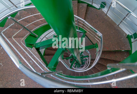 Spiral multi-flight stairway with metal handrails seen from the top of the staircase Stock Photo