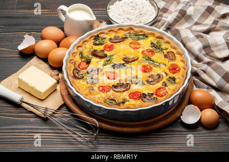 Baked homemade quiche pie in ceramic baking form, eggs and cream Stock Photo