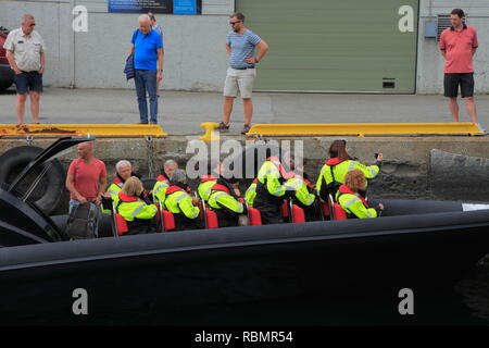 People wearing protective clothing get ready to take a rigid-inflatable (RIB) boat tour from the Hanseatic wharf in Bergen harbour, Norway. Stock Photo