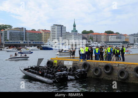 A group of people put on life jackets and get ready to take a rigid-inflatable (RIB) boat tour from the quay in Bergen harbour, Norway. Stock Photo